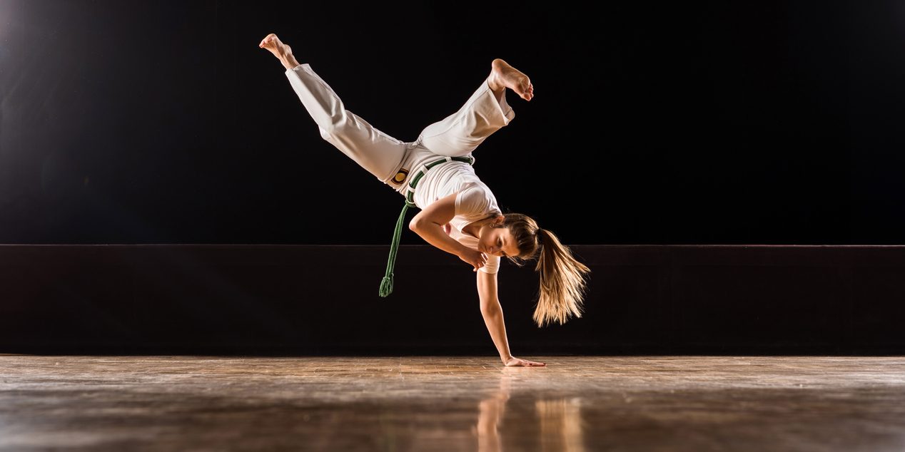 Capoeira female athlete doing a handstand on sports training in a health club. Copy space.